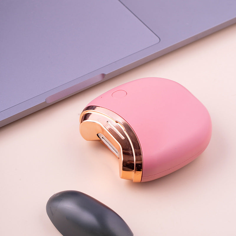 Coupe-ongles électrique rose avec tête de coupe visible et capuchon retiré, près d'un ordinateur
