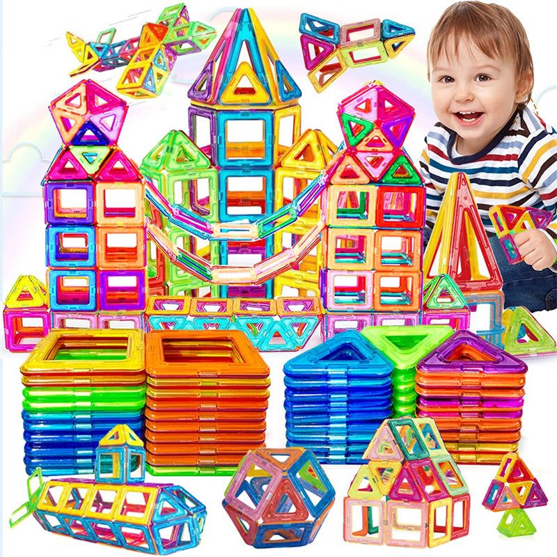  Jeu de construction magnétique coloré avec un château, des formes assemblées et des piles de pièces carrées et triangulaires, à côté d’un enfant .
