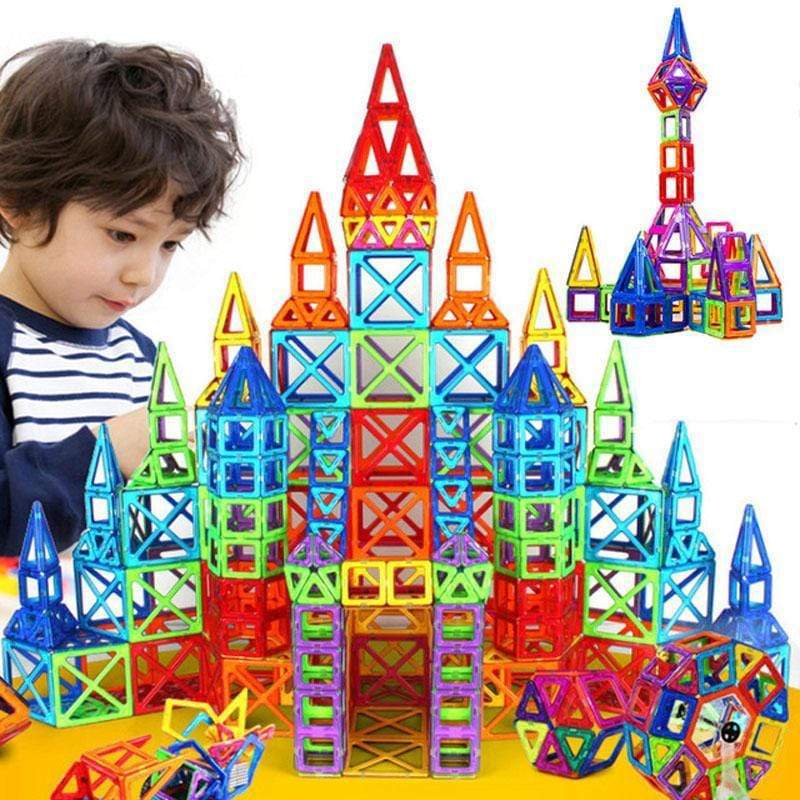 Enfant devant un grand château multicolore construit avec des pièces magnétiques carrées et triangulaires .