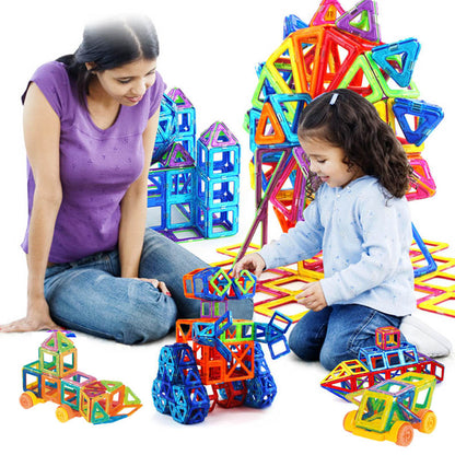 Une adulte et une enfant assemblant des pièces magnétiques colorées, entourées de constructions en forme de véhicules et de tours. 